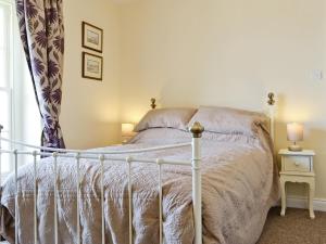 a bedroom with a white bed and a window at Granary Cottage in Penrhyn Bay