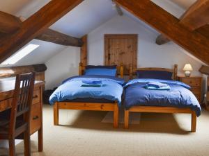 LlanwndaにあるGlanrafon Isafの木製天井の屋根裏部屋のベッドルームにベッド2台が備わります。