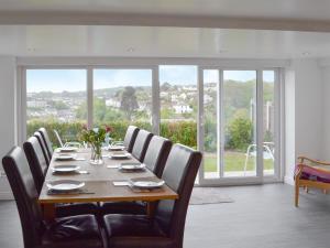 a dining room with a long table with chairs and windows at Samphire in Brixham