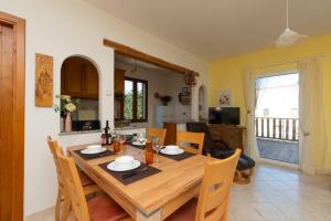 a kitchen and dining room with a wooden table and chairs at casa su rimediu in Orosei