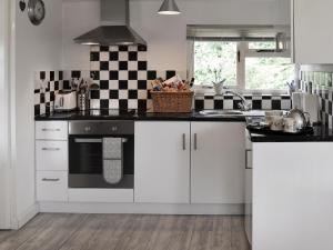 a kitchen with white cabinets and black and white tiles at The Chicken Shed in Ruckinge