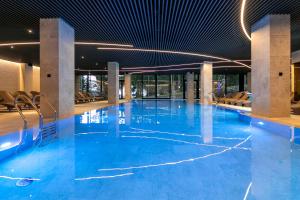 a large swimming pool with blue water in a building at HVOYA Apart-Hotel & SPA in Bukovel