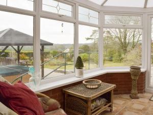 a conservatory with windows and a table and a view at Green Haven in Narberth