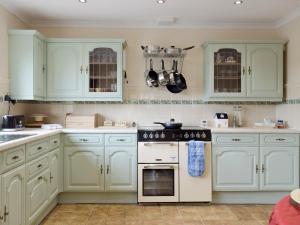 uma cozinha com armários brancos e um forno com placa de fogão em Green Haven em Narberth