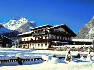 un edificio cubierto de nieve frente a una montaña en Madlgut, en Lofer