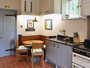 eine Küche mit einer Theke und einem Tisch darin in der Unterkunft The Coach House The Old Rectory in Buckland St Mary