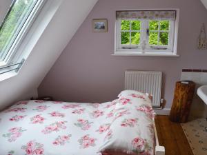 a bedroom with a bed with a floral bedspread at The Coach House The Old Rectory in Buckland St Mary