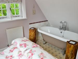 a bathroom with a bath tub and a bed at The Coach House The Old Rectory in Buckland St Mary