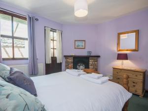 a bedroom with a large white bed with a fireplace at Apple Tree Cottage in Scalby