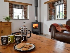 a table with cookies and two cups and a stove at Paxton View Barn in Llanddarog