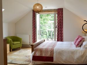 um quarto com uma cama, uma janela e uma cadeira em Paxton View Barn em Llanddarog