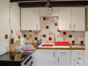 cocina con armarios blancos y encimera en Bryn Rhos Goch, en Dolwyddelan