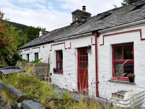 una antigua casa blanca con puertas y ventanas rojas en Bryn Rhos Goch, en Dolwyddelan