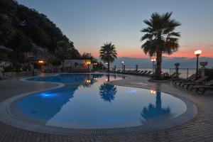 a large swimming pool with palm trees and a sunset at Hotel Residence Tramonto in Rodi Garganico