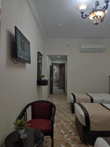 a room with two beds and a table and a tv at اوتاد المتحدة in Al ‘Azīzīyah