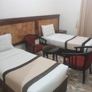 a room with three beds and a chair and adozen at اوتاد المتحدة in Al ‘Azīzīyah
