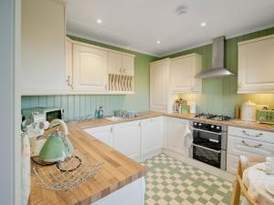 a kitchen with white cabinets and a tea kettle on a counter at Dunultach Cottage in Ronachan