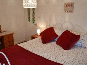 - une chambre avec un lit et 2 oreillers rouges dans l'établissement Wild Flower Cottage, à Youlgreave