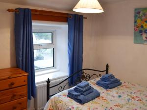 - une chambre avec un lit doté de rideaux bleus et de serviettes bleues dans l'établissement Wild Flower Cottage, à Youlgreave