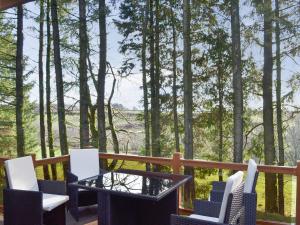 una mesa y sillas en una terraza con árboles en Oak Lodge, en Clatworthy