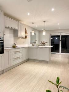 a kitchen with white cabinets and a kitchen island at Modern, central bungalow with Luxury Hot tub in Bournemouth
