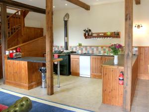 una gran cocina con armarios de madera y una escalera en The Coach House - Exg, en Upton