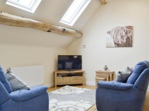 a living room with two blue chairs and a tv at No, 2 Ash Cottage in Quatt