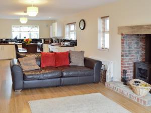 a living room with a leather couch and a fireplace at Ryandale in Longhirst