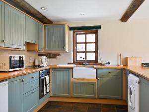 a kitchen with green cabinets and a window at The Stables in Hornsea