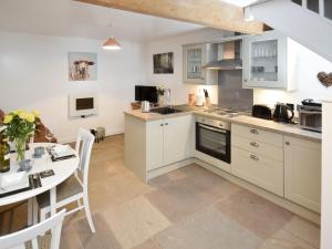 a kitchen with white cabinets and a table and a dining room at The Stable - 30562 in Whalley