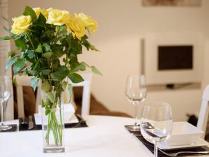 a vase of yellow roses sitting on a table with glasses at The Stable - 30562 in Whalley