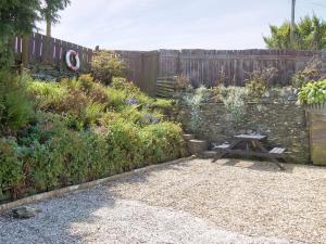 a garden with a wooden fence and a picnic table at Kilcummer Stables in Tintagel +2 photos