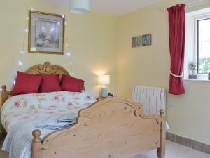 a bedroom with a wooden bed with red pillows at Mill Cottage in Stillington