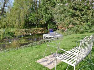 a table and a chair in the grass near a pond at Mill Cottage in Stillington