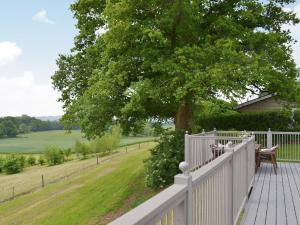 a porch with a white fence and a tree at Wattles-e4527 in Uplowman