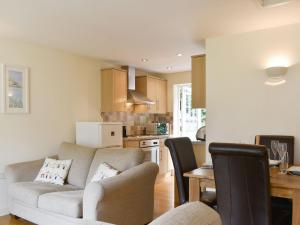 sala de estar con sofá y cocina en Endless Summer Cottage, en Camelford