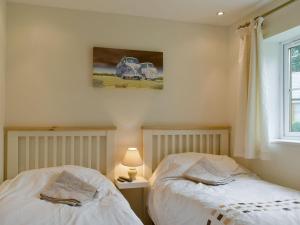 twee bedden in een slaapkamer met een foto aan de muur bij Endless Summer Cottage in Camelford