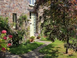uma casa de tijolos com uma porta e um quintal com flores em Passion Flower Cottage - E1468 em Stowford