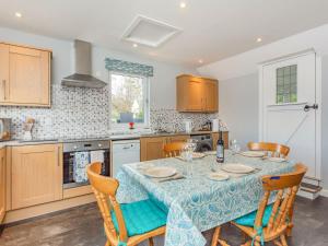 a kitchen with a table with chairs and a tablecloth on it at Seathrift Cottage in Ardersier
