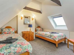 a attic bedroom with two beds and a mirror at Seathrift Cottage in Ardersier