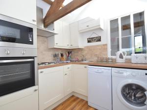 a kitchen with white cabinets and a washer and dryer at Buzzards View in Kingswear