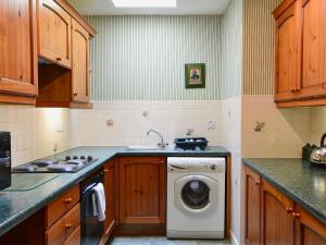 uma cozinha com uma máquina de lavar roupa e um lavatório em Perriwinkle-mgh em Akeld
