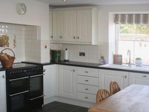 a kitchen with white cabinets and a black oven at Werescote View in Burlescombe