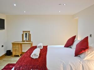 a bedroom with a white bed with red pillows at Werescote View in Burlescombe