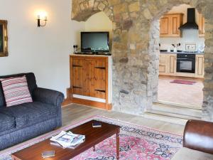 a living room with a couch and a stone wall at Cobweb Cottage in Elsdon