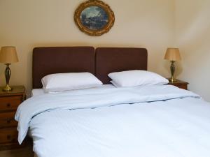 duas camas com lençóis brancos e uma foto na parede em Cobweb Cottage em Elsdon