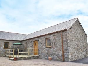 a stone house with a wooden porch and a deck at The Parlour - Op4 in Carmarthen