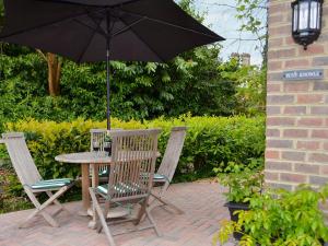 a table and chairs with an umbrella on a patio at Petit Knowle in Cuckfield