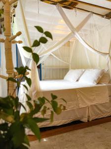 1 cama blanca con dosel en una habitación en Casa do Rio, en Caraíva