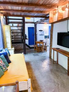 a living room with a tv and a dining room at Casa do Rio in Caraíva